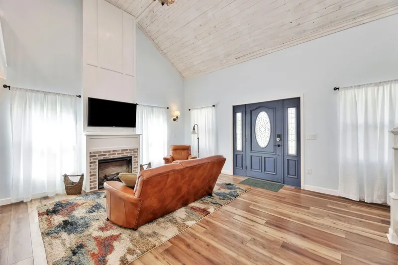 Living room with fireplace, leather seating and vaulted ceiling